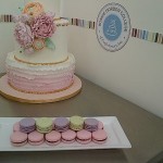 Bonnie Gordon School of Confectionary Arts, white floral cake and macaroons displayed on steel kitchen cart